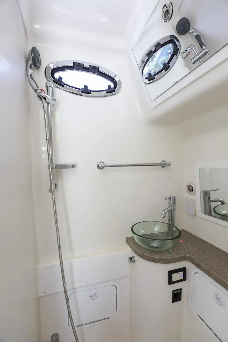 Slide: The Image of 2020 Regulator 41 boat bathroom with shower, sink, and porthole windows. - 29