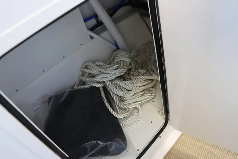 Slide: The Image of Storage compartment in 2025 Sea Ray 250SDX boat with coiled rope and black bag. - 10