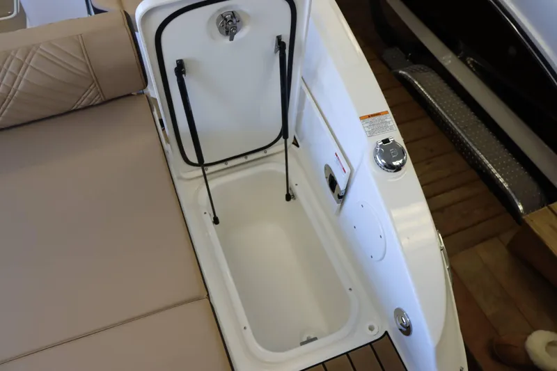 Slide: The Image of 2025 Sea Ray 250SDX boat storage compartment with open lid and beige seating. - 32