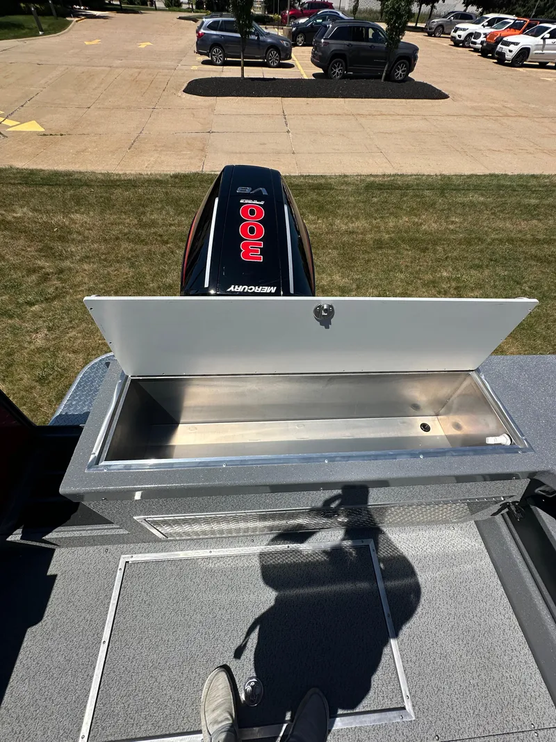 Slide: The Image of 2024 Spartan 220 Maximus boat with open storage compartment and outboard motor. - 19