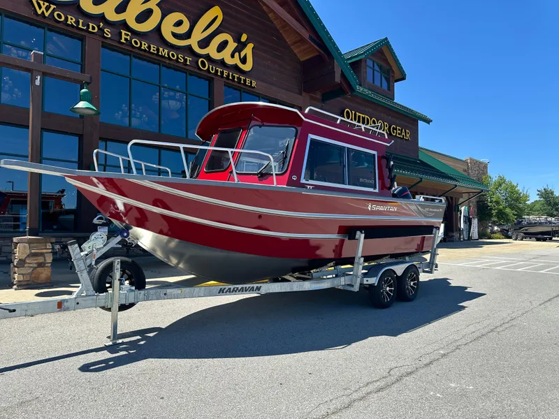 Slide: The Image of 2024 Spartan 220 Maximus boat on trailer outside Cabela's outdoor gear store. - 2