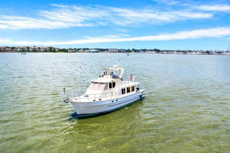 Slide: The Image of 2010 North Pacific 43 Pilothouse boat on calm waters with a scenic coastal backdrop. - 29