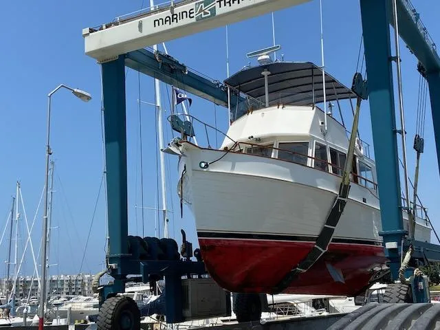 Slide: The Image of 1969 Grand Banks 42 Classic yacht in dry dock, suspended by a marine travel lift. - 30