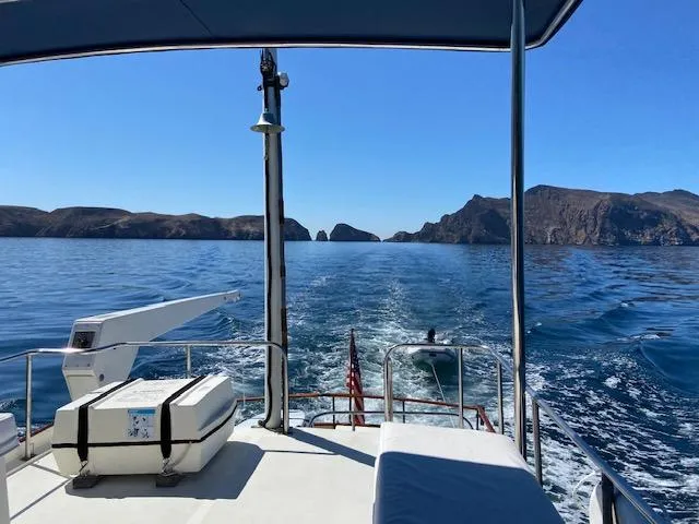 Slide: The Image of Grand Banks 42 Classic yacht cruising near rocky coastline, clear blue sky and water. - 38