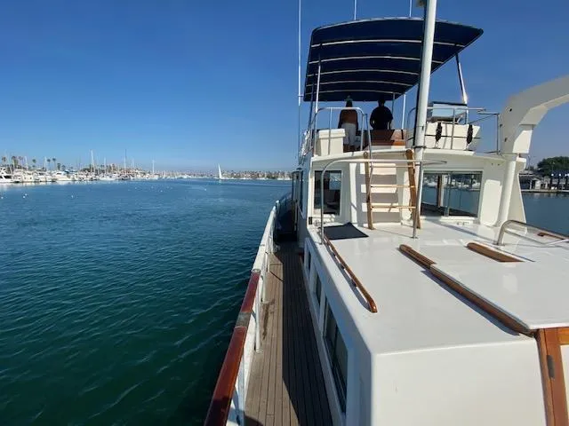 Slide: The Image of 1969 Grand Banks 42 Classic yacht on calm water, featuring a spacious deck and canopy. - 43