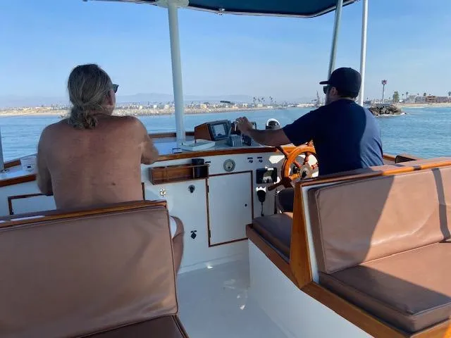 Slide: The Image of Two people navigating a 1969 Grand Banks 42 Classic boat on calm waters. - 44