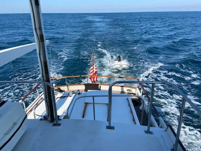 Slide: The Image of 1969 Grand Banks 42 Classic yacht cruising with a small boat in tow on open sea. - 45