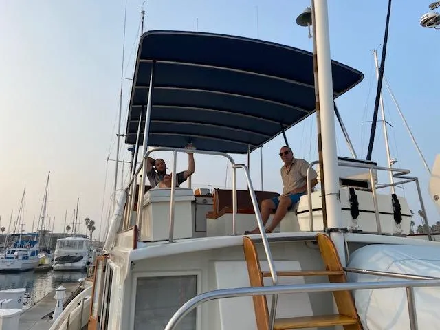 Slide: The Image of Two people relaxing on a 1969 Grand Banks 42 Classic yacht at a marina. - 46