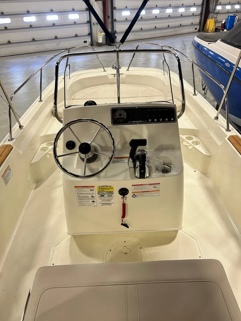 Slide: The Image of 2024 Boston Whaler 170 Montauk boat interior with steering console in a showroom. - 2
