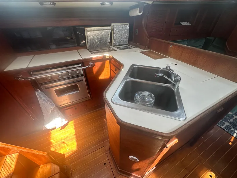Slide: The Image of 1987 Sabre 42 yacht kitchen with stove, sink, and wooden cabinetry. - 14