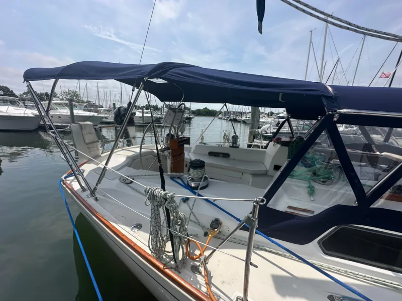 Slide: The Image of 1987 Sabre 42 sailboat docked at marina, featuring blue canopy and clean deck. - 5