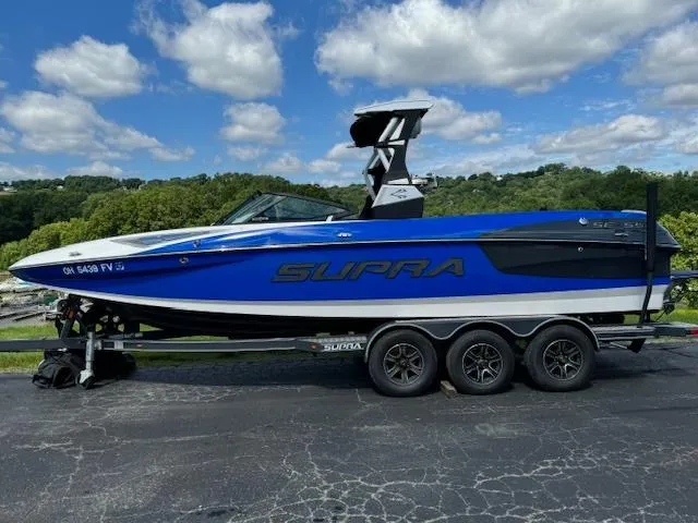 The Image of 2018 Supra SE boat on a trailer under a blue sky with clouds. - 1