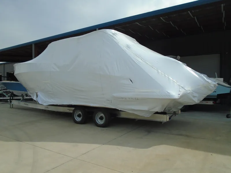Slide: The Image of 2024 Regal 36XO boat covered in white tarp on a trailer. - 36