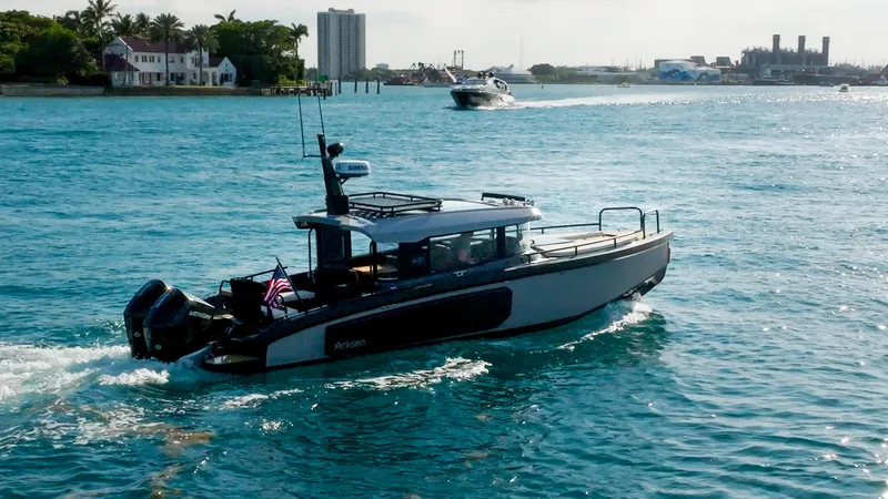 Slide: The Image of Arksen 30 boat cruising on blue water, 2025 model, with coastal buildings in the background. - 14