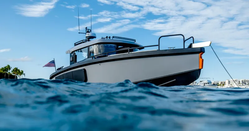 Slide: The Image of 2025 Arksen 30 boat on water with American flag, clear sky background. - 2