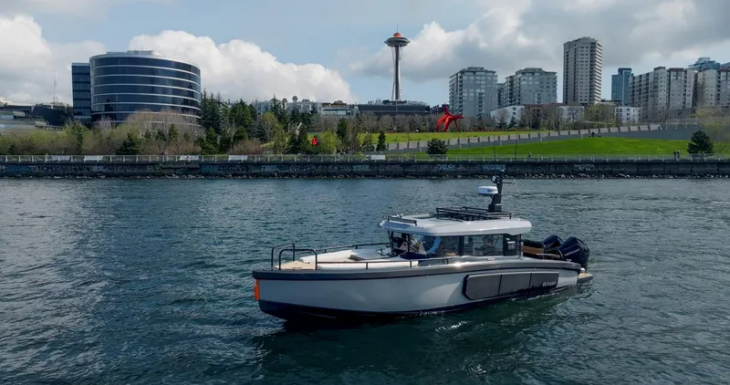 Slide: The Image of Arksen 30 boat cruising near urban waterfront with cityscape and iconic tower in the background, 2025. - 20