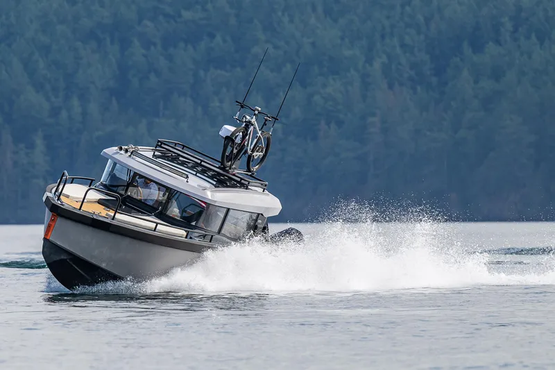 Slide: The Image of 2025 Arksen 30 boat cruising on water with forested background. - 21