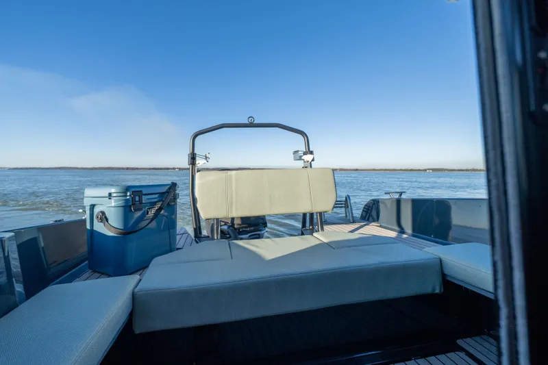 Slide: The Image of Arksen 28 boat 2025 model with seating and cooler on a calm lake. - 6