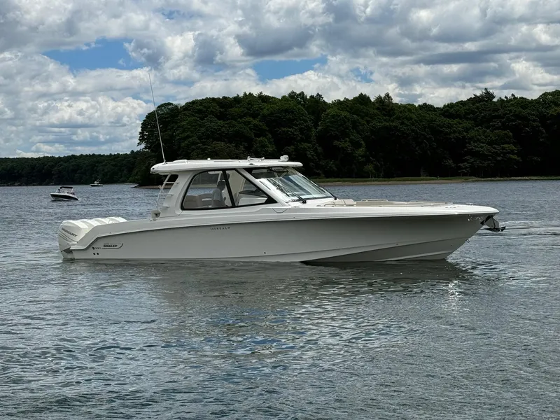 Slide: The Image of 2020 Boston Whaler 380 Realm boat cruising on a calm lake with forested shoreline. - 0
