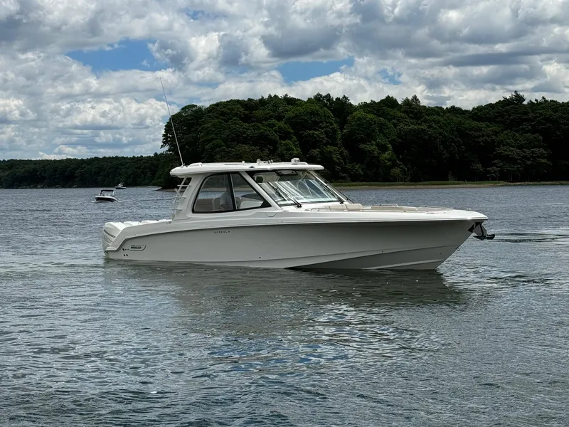Slide: The Image of 2020 Boston Whaler 380 Realm boat cruising on a lake with a forested shoreline. - 1