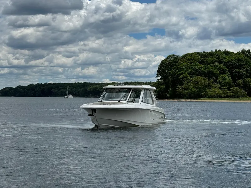 Slide: The Image of 2020 Boston Whaler 380 Realm cruising on a lake with a forested shoreline. - 10