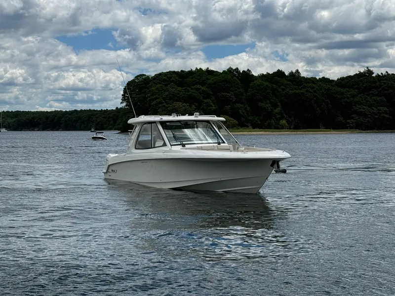 Slide: The Image of 2020 Boston Whaler 380 Realm boat cruising on a lake with forested shoreline. - 2