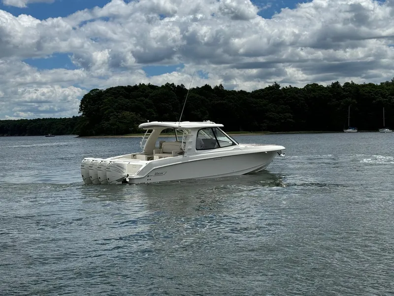 Slide: The Image of 2020 Boston Whaler 380 Realm boat cruising on a lake with a forested shoreline. - 3