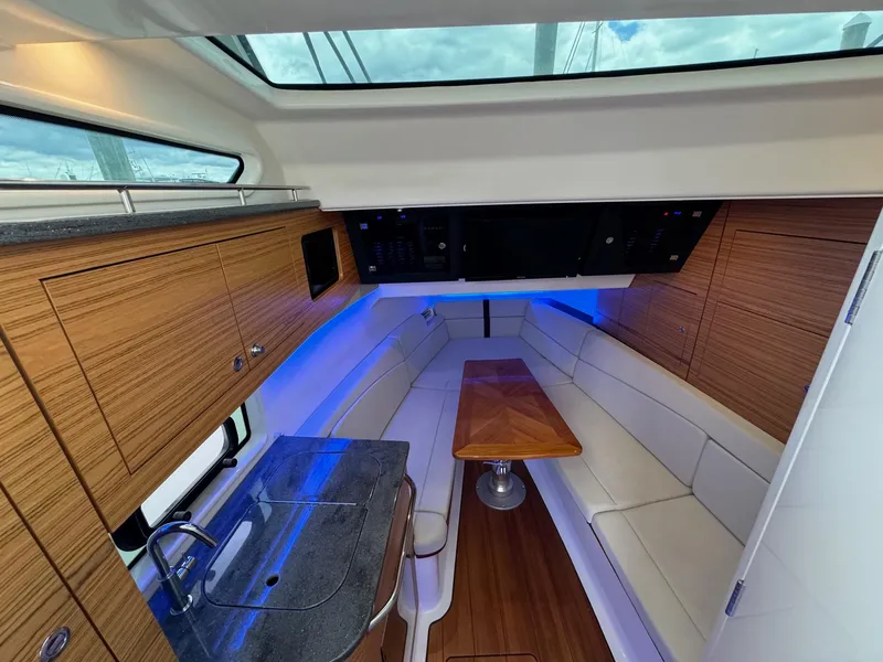 Slide: The Image of Interior of 2020 Boston Whaler 380 Realm with kitchenette, seating area, and wooden table. - 36