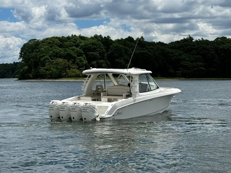 Slide: The Image of 2020 Boston Whaler 380 Realm boat cruising on a lake with forested shoreline. - 4