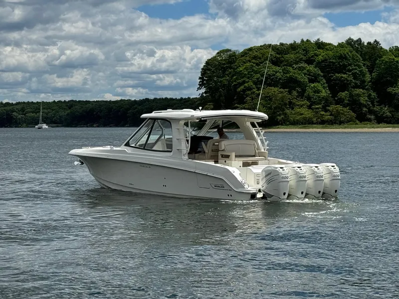 Slide: The Image of 2020 Boston Whaler 380 Realm boat cruising on a lake with lush green trees in the background. - 7