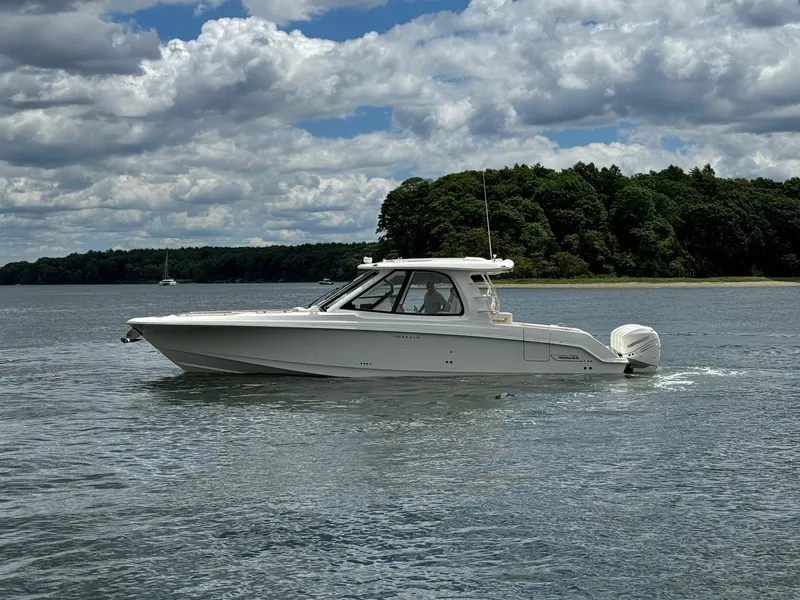 Slide: The Image of 2020 Boston Whaler 380 Realm boat cruising on a lake with a forested shoreline. - 8