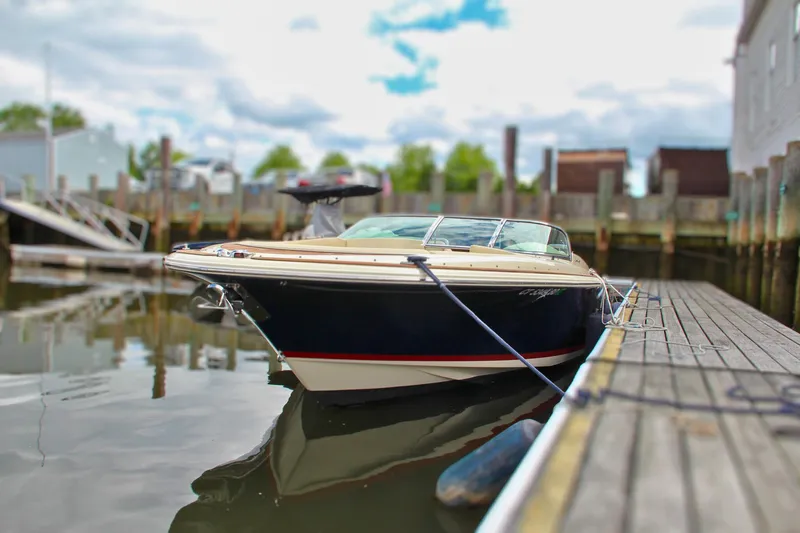 Slide: The Image of 2013 Chris-Craft Launch 28 boat interior at a marina, featuring luxurious seating and wooden deck. - 10