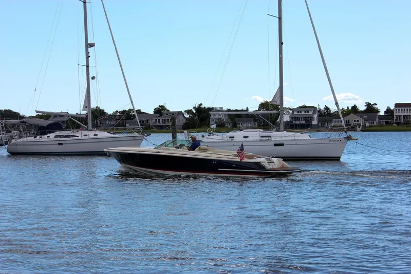 Slide: The Image of 2013 Chris-Craft Launch 28 boat cruising near sailboats in a scenic harbor. - 62