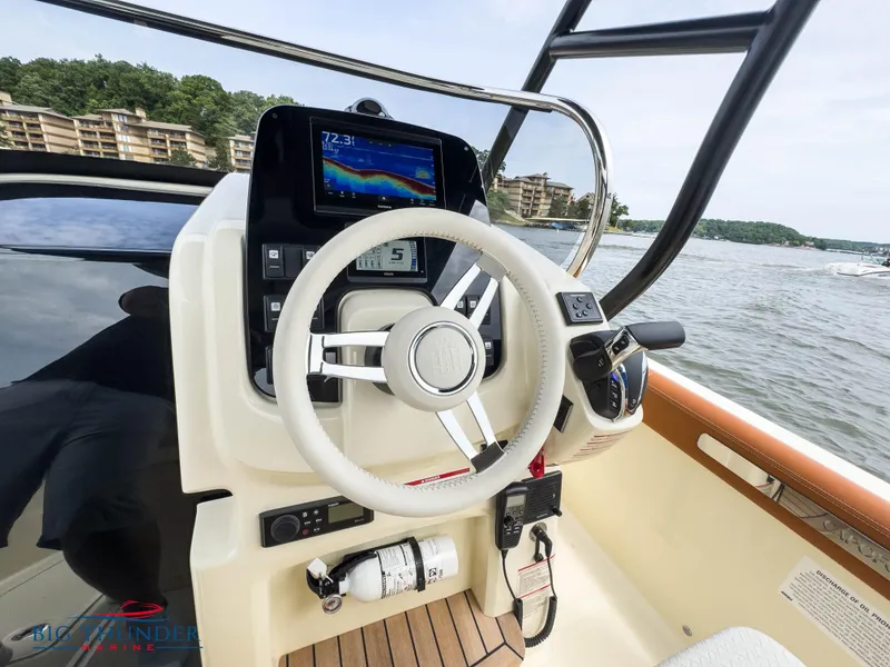 Slide: The Image of Capoforte FX240 2024 boat dashboard with steering wheel and navigation display on a lake. - 20