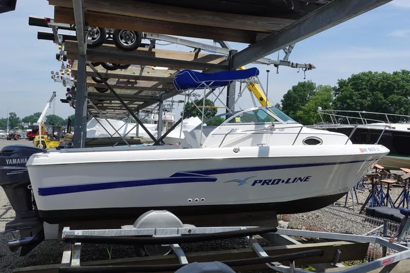 The Image of 1999 Pro-Line 221 Walk boat on trailer, stored outdoors, with Yamaha outboard motor. - 0