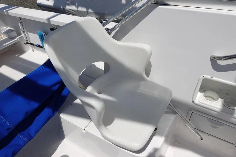 Slide: The Image of White seat on 1999 Pro-Line 221 Walk boat deck, with blue cover nearby. - 13