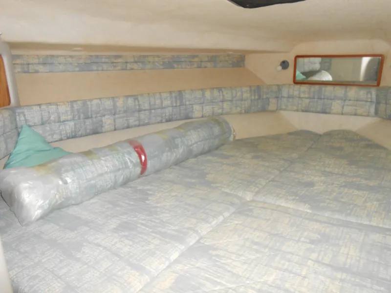 Slide: The Image of Interior cabin of 1991 Sea Ray Sundancer 310 with cushioned bedding and a small window. - 10