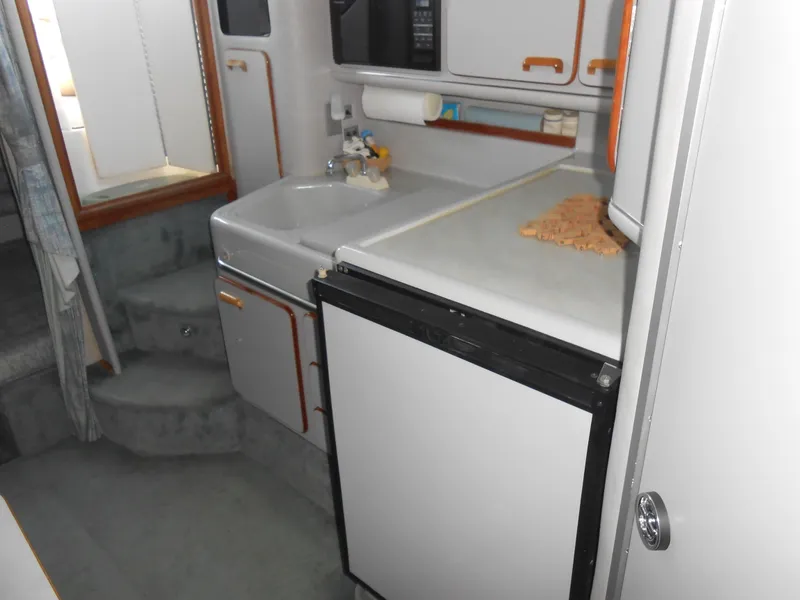 Slide: The Image of 1991 Sea Ray Sundancer 310 boat interior kitchen with sink, countertop, and refrigerator. - 12