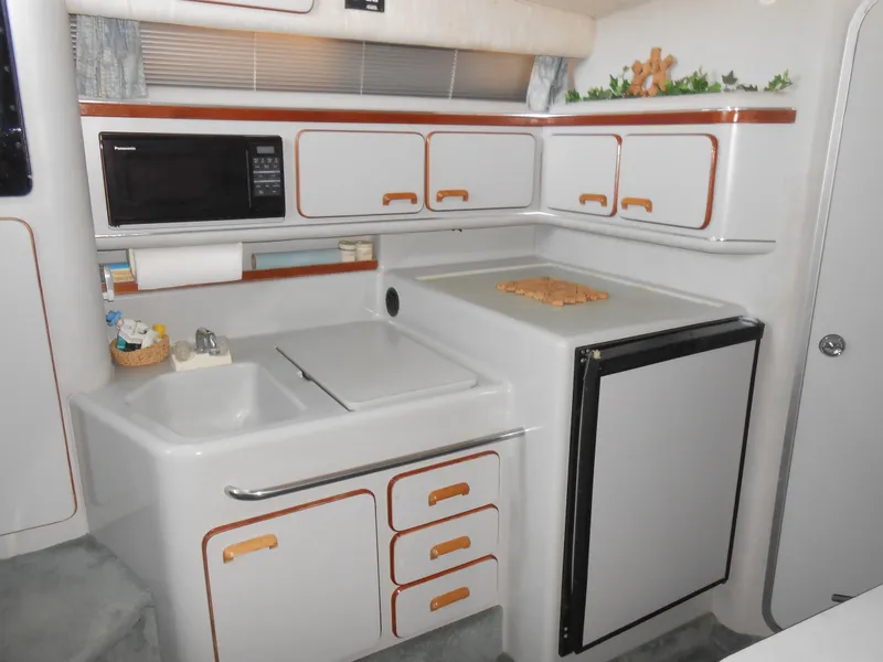 Slide: The Image of 1991 Sea Ray Sundancer 310 galley with sink, microwave, and refrigerator. - 14