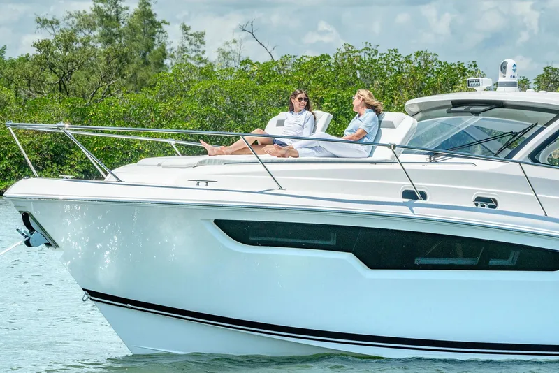 Slide: The Image of 2025 Pursuit OS 405 yacht with two people relaxing on deck, surrounded by lush greenery. - 5