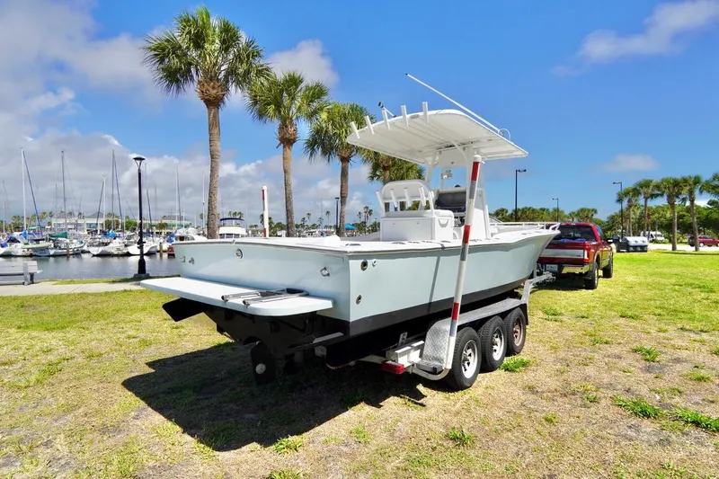 Slide: The Image of 1993 Ocean Runner 27 CC boat on trailer near marina with palm trees. - 23
