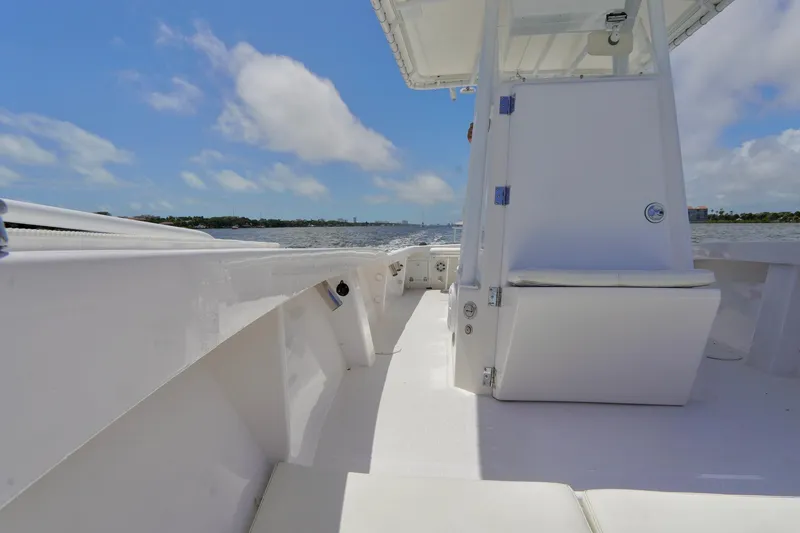 Slide: The Image of 1993 Ocean Runner 27 CC boat interior with white seating and open deck, under clear blue sky. - 9