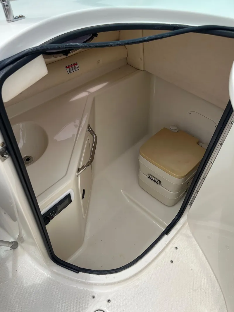 Slide: The Image of 2003 Sea Ray 270 boat interior with compact bathroom and portable toilet. - 14