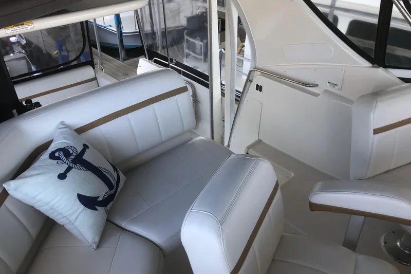 Slide: The Image of 2005 Carver 41 Cockpit Motor Yacht interior with white seating and nautical-themed pillow. - 27