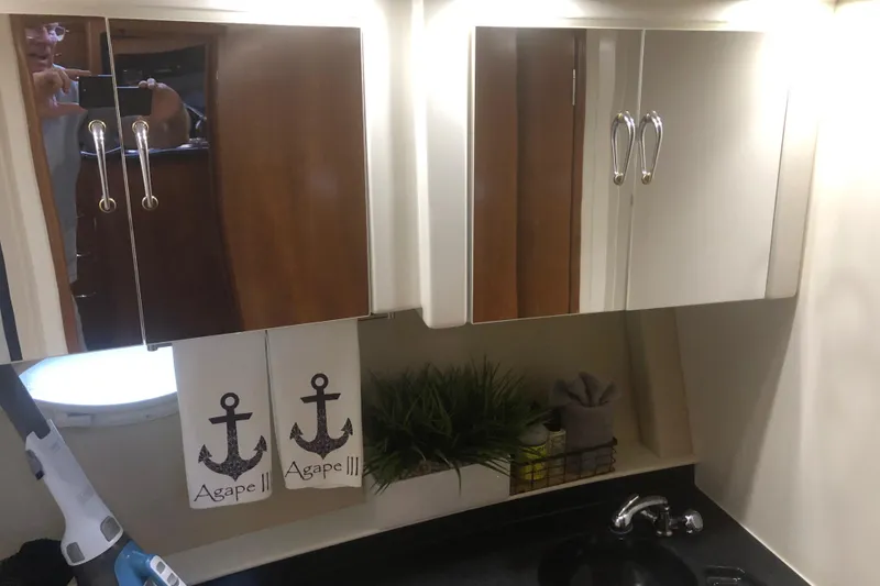 Slide: The Image of 2005 Carver 41 Cockpit Motor Yacht bathroom with mirror cabinets and anchor-themed towels. - 48