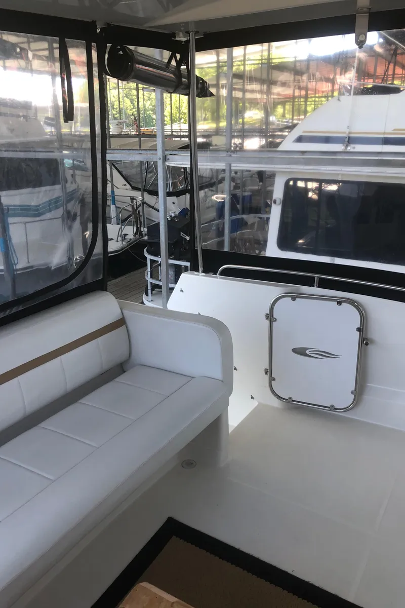 Slide: The Image of 2005 Carver 41 Cockpit Motor Yacht interior with white seating and dock view. - 14