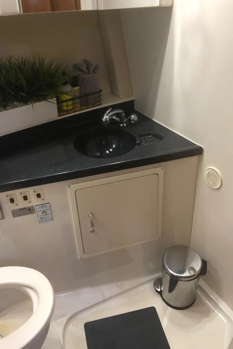 Slide: The Image of 2005 Carver 41 Cockpit Motor Yacht bathroom with black countertop and sink. - 47