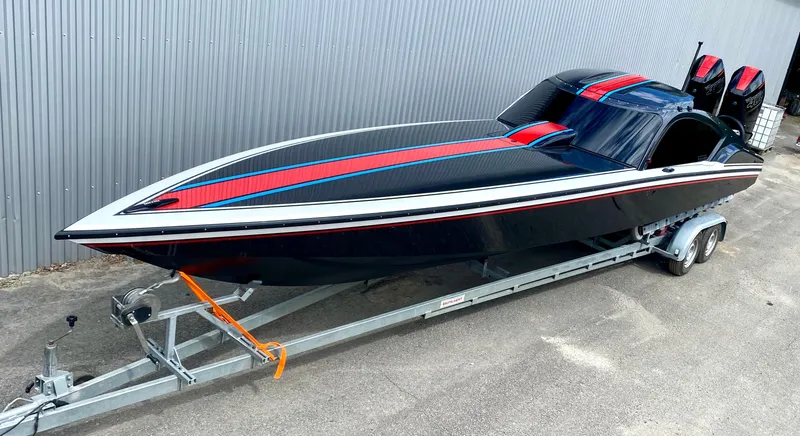 Slide: The Image of 2024 Nitra Boats 30 SkyTop on trailer, black with red and blue stripes. - 3