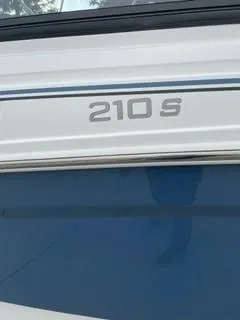 Slide: The Image of 2024 Tahoe 210 S boat model nameplate on blue and white exterior. - 1