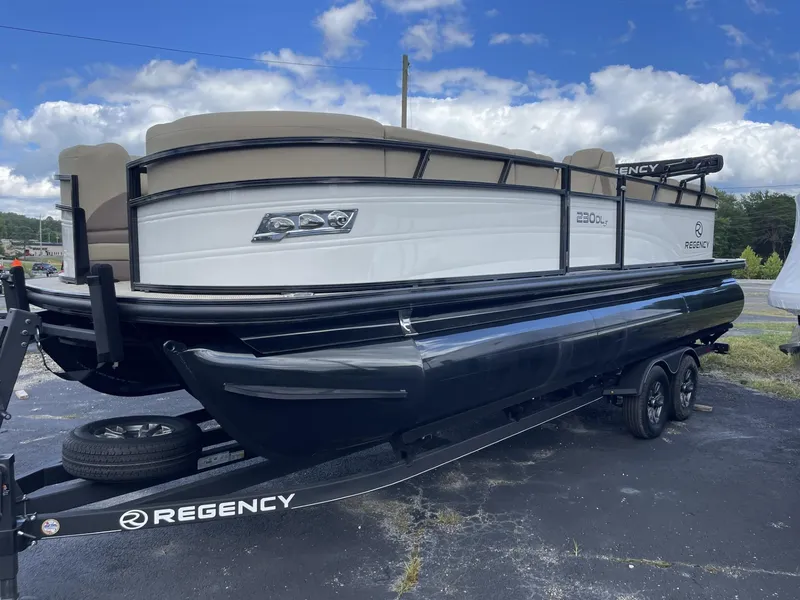 Slide: The Image of 2024 Regency 230 DL3 pontoon boat on a trailer under a blue sky. - 2